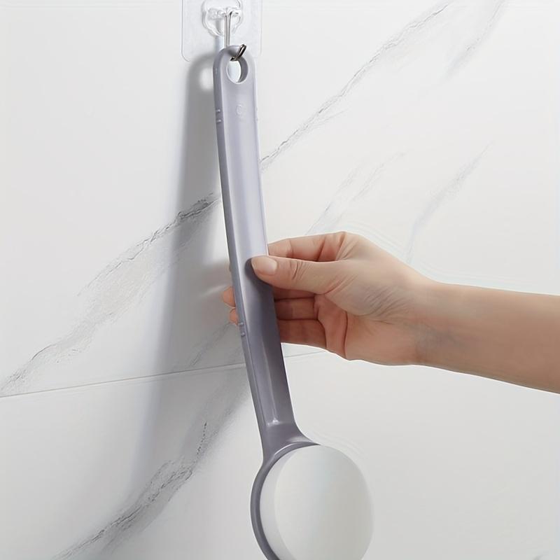 Aplikátor tělového mléka s dlouhou rukojetí, vybavený kartáčem na záda a houbičkou, určený k použití po koupání.