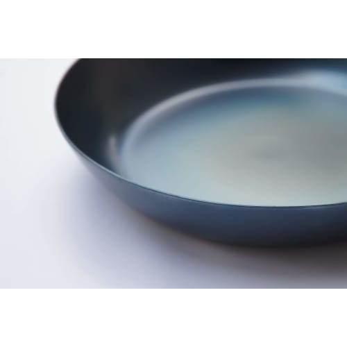 This 24cm iron skillet with a plain wood handle is made in Japan and is suitable for induction cooktops. It's lightweight and requires no seasoning. P