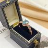 Anillo Yintai de Oro Rosa con Topacio Azul, Circonita Ovalada y Banda Trenzada - Exquisita Joyería de Lujo Ligero