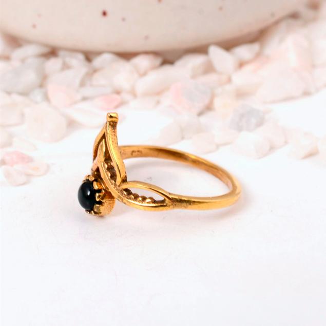 Ornate Black Onyx Crown Ring: Gold-toned jewelry with a round black cabochon and a delicate lotus or tiara-style setting.