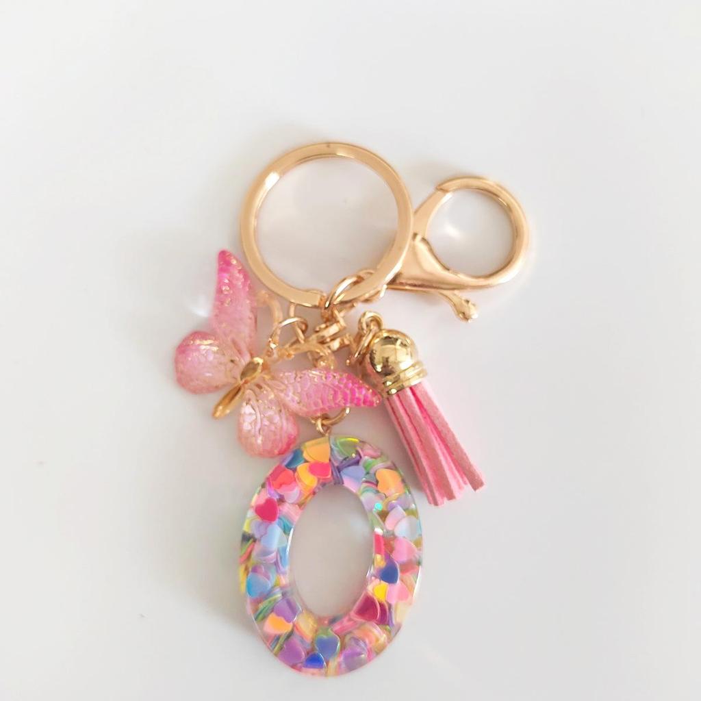 Rosa Glitzer Epoxidharz Schlüsselanhänger mit englischem Buchstaben und Schmetterlingsquaste