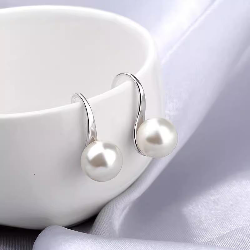 Kulaté stříbrné náušnice ve tvaru jehly s kulatými perlovými háčky. Tvarovaná jako lžíce, jednoduchá a elegantní.