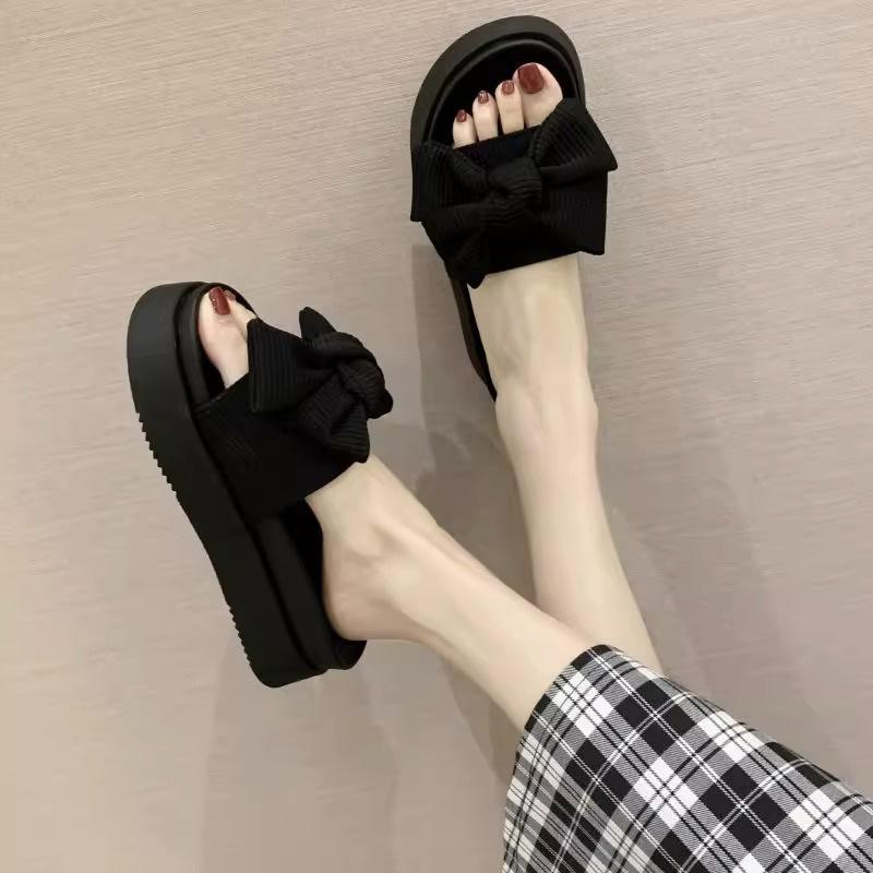 Schwarze, mit Schleife versehene Ein-Wort-Slipper für Damen-Sommerbekleidung, neue Muffin-Dicksohle, rutschfest, fortschrittliche, coole Slipper