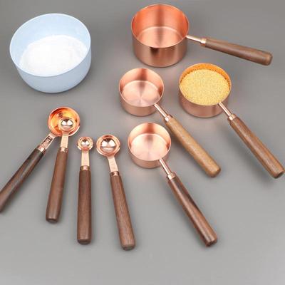 סט כפות וכוסות מדידה מנירוסטה בגימור זהב ורוד וידיות עץ - 8 חלקים