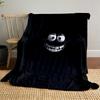 A glowing, cartoonish face with wide eyes and a big toothy grin on black. for all seasons blanket lunch break throw gift