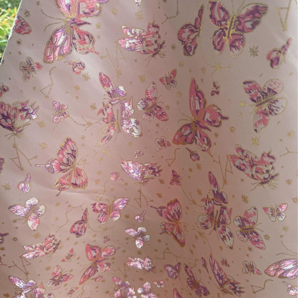 Ethnischer Jacquardstoff für Damen- und Kinderbekleidung in Rosa, Lila, Rot und Gold.