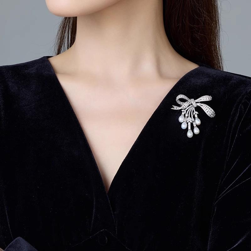 Broșă cu ciucure în formă de fundă cu perle, cu un simț al designului feminin, o broșă nișată și un palton de costum la modă