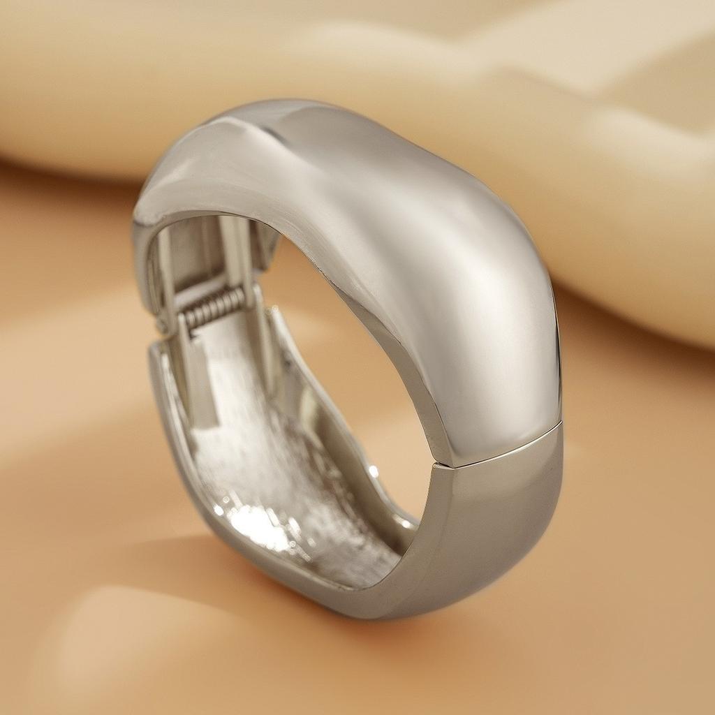 Pulsera de moda con textura metálica lisa y diseño geométrico en forma de cruz.