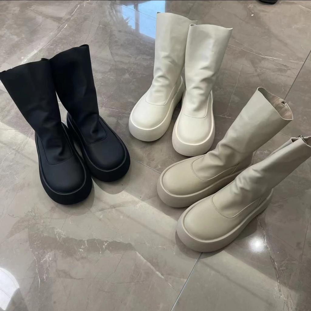 Modelka na přehlídkovém mole v minimalistickém stylu podzim 2025, cigaretové kozačky, na jeden pedál, tenké kozačky mohou být slané i sladké, korejská verze elastických kozaček na silné podrážce