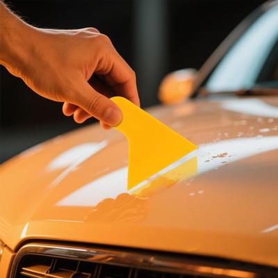 Gelber Schaber, zum Entfernen von Autofolienkleber und zum Verhindern des Ablösens von Planeraufkleberkanten.
