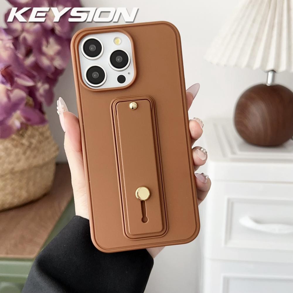 

KEYSION Wrist Strap Phone Case for iPhone 16 17 Pro Max 17 Air 16 Plus Wristband Kickstand Matte Shockproof Back Cover for iPhone 16 Pro Max коричневий