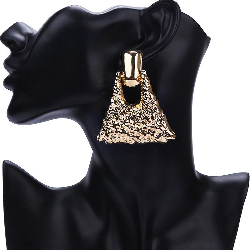 

Женская золотая сумка и серьги с преувеличенной матовой текстурой