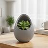 A modern, decorative gray plant pot in the shape of a nest for plants.
