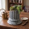 Gray designer flowerpot in the shape of a Greek column for plants