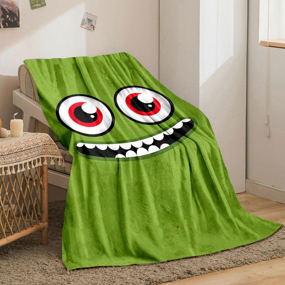 A green face with large red eyes and a wide, toothy grin. for all seasons blanket lunch break throw gift