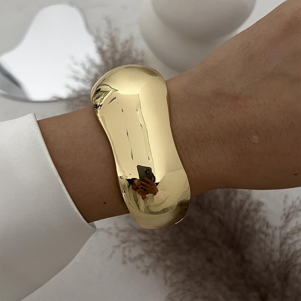 Pulsera de moda con textura metálica lisa y diseño geométrico en forma de cruz.