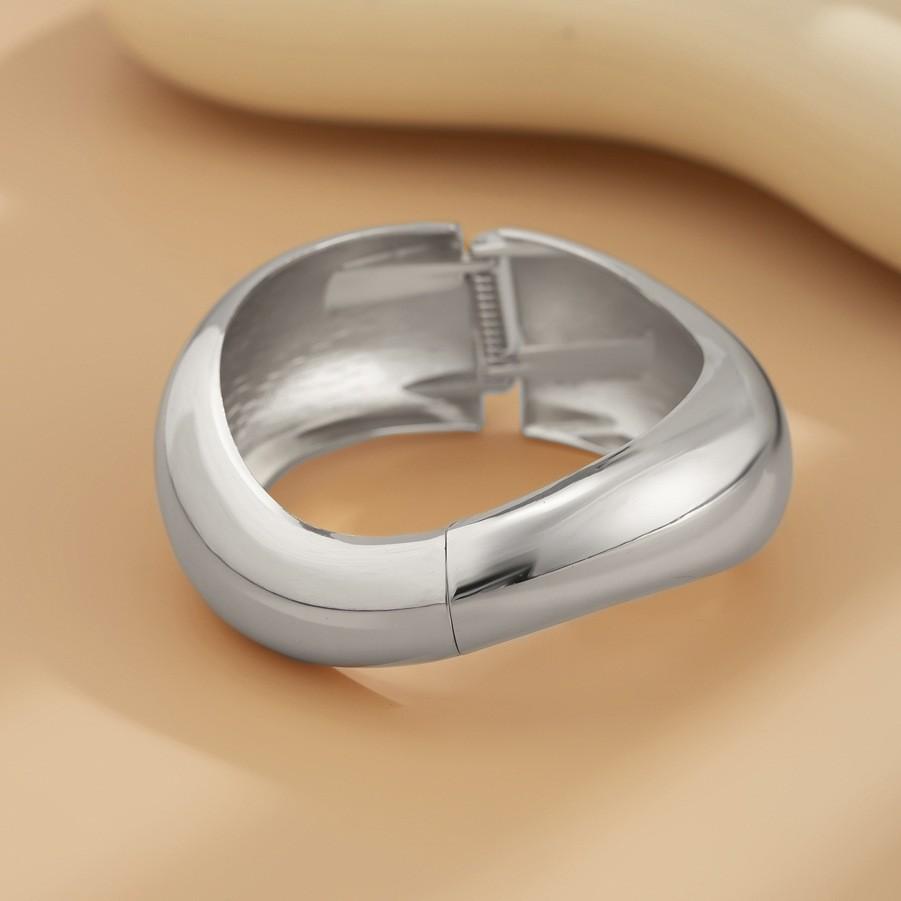 Pulsera de moda con textura metálica lisa y diseño geométrico en forma de cruz.