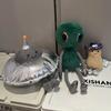 Peluche Espace Mignonne Alien Vert Souriant Soucoupe Volante Argentée Poupées Extraterrestres Douces Remplies Cadeau Adorable pour Fans de Science-Fiction Décoration de Maison