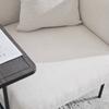 Poltrona individual moderna com encosto de tecido confortável e dois compartimentos de arrumação, complementada por uma mesa lateral prática.