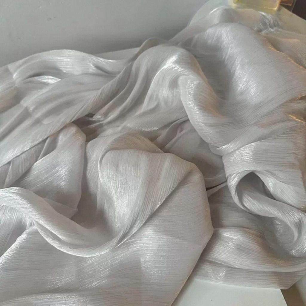 Soft shiny creased organza fabric with a smooth texture suitable for wedding dresses formal gowns and designer clothing fabrics
