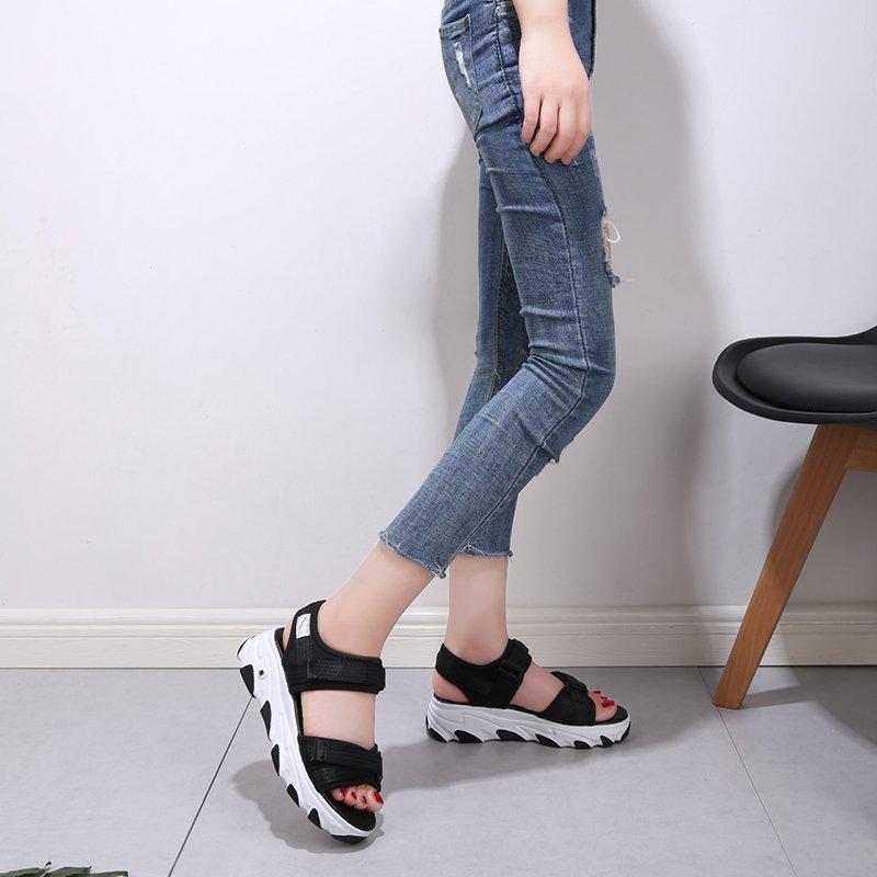 Dívky nosí malé vonné sandály s plochou a tlustou spodní částí, sportovní sandály, elegantní a pohodlné dámské módní boty