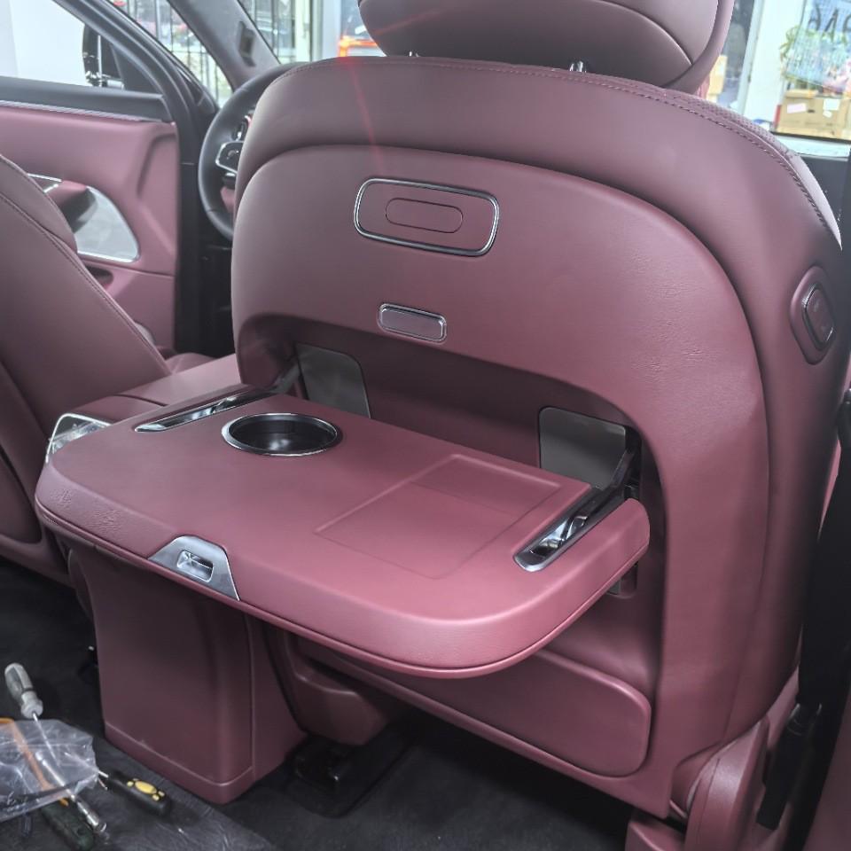 

Multifunctional Rear Seat Headrest Table with Cup Holder & Wireless Charging for Business Vehicle Interior Upgrade.