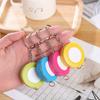 A Stylish Keychain Measuring Tape In Vibrant Colors, Featuring A 1.5-Meter Retractable Design, Perfect for Measuring Clothing Sizes