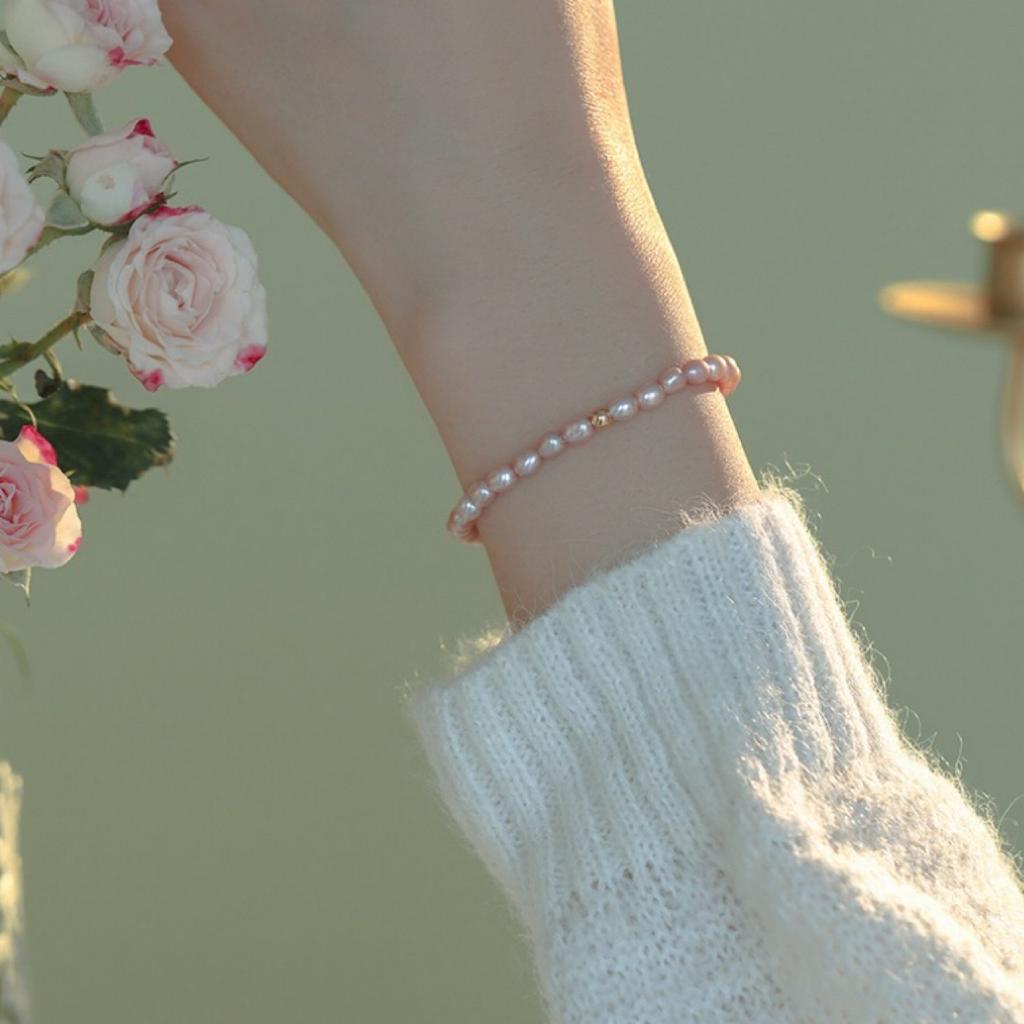 Super delicate, soft-toned orange, pink, and purple natural freshwater pearl bracelet with a small, bead-like design, elastic, and minimalist style