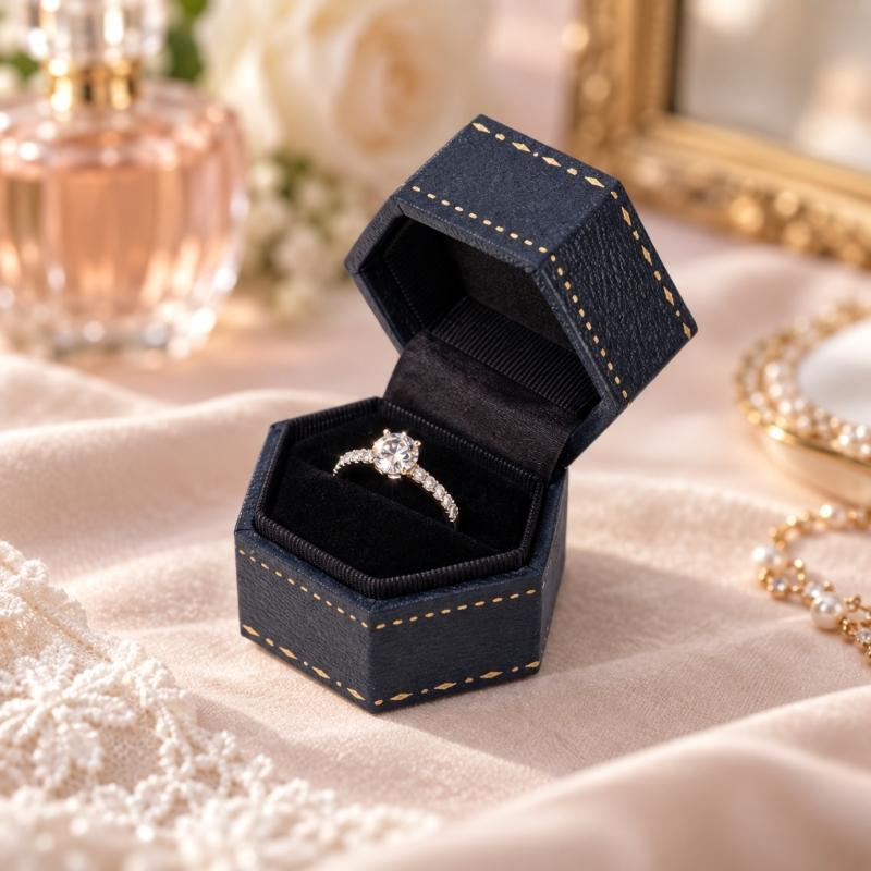 Hexagonal Ring Presentation Box with Black Interior, Gold-Tone Border Pattern, and Attached Lid for Retail Display