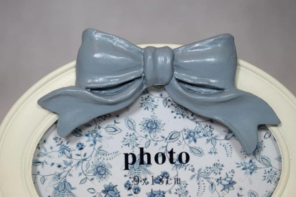 A charming white oval-shaped frame decorated with a bow