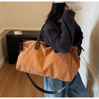 Ruční cestovní taška a crossbody fitness taška vyzařují smysl pro sofistikovanost a módu.