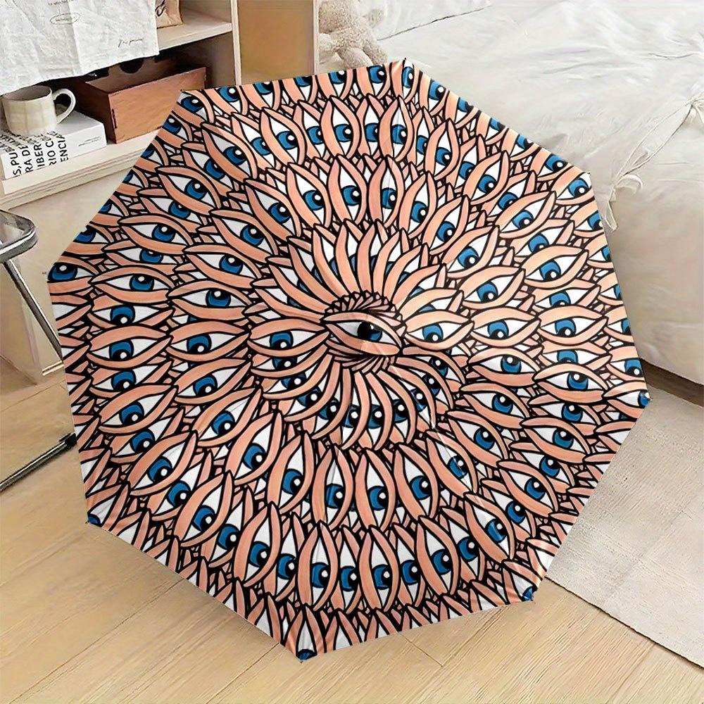 

Folding Umbrella The umbrella features a radial pattern of eyes surrounded by geometric shapes radiating from the center. Fit