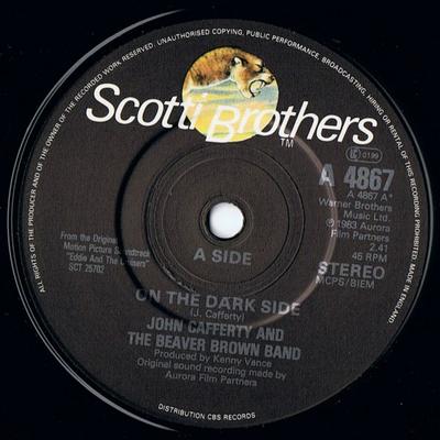 7 collu plate JOHN CAFFERTY & THE BEAVER BROWN BA - On The Dark Side A4867 Scotti Bros. Re 1983 Lielbritānijas Skaņu celiņi un Mūzikli Lietots
