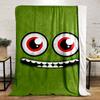 A green face with large red eyes and a wide, toothy grin. for all seasons blanket lunch break throw gift