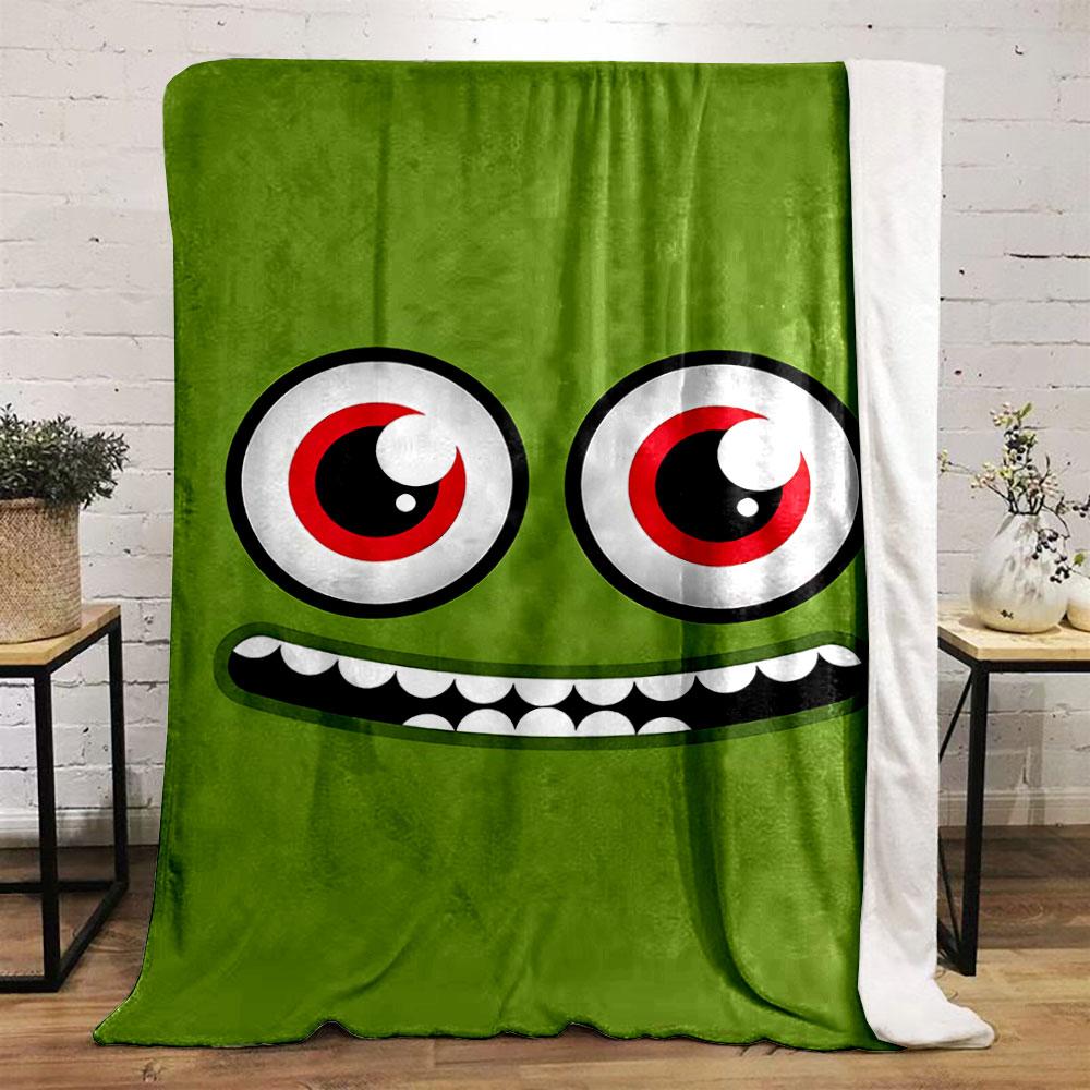 A green face with large red eyes and a wide, toothy grin. for all seasons blanket lunch break throw gift
