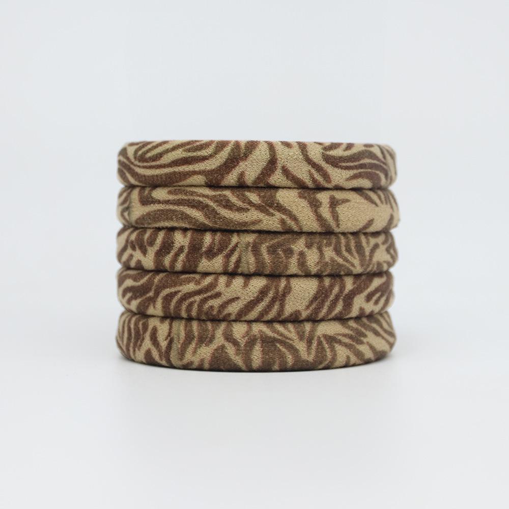 Ein Damen-Haargummi mit einem Handtuch-Haargummi mit Leopardenmuster und einem Zopfgummi schädigt das Haar nicht