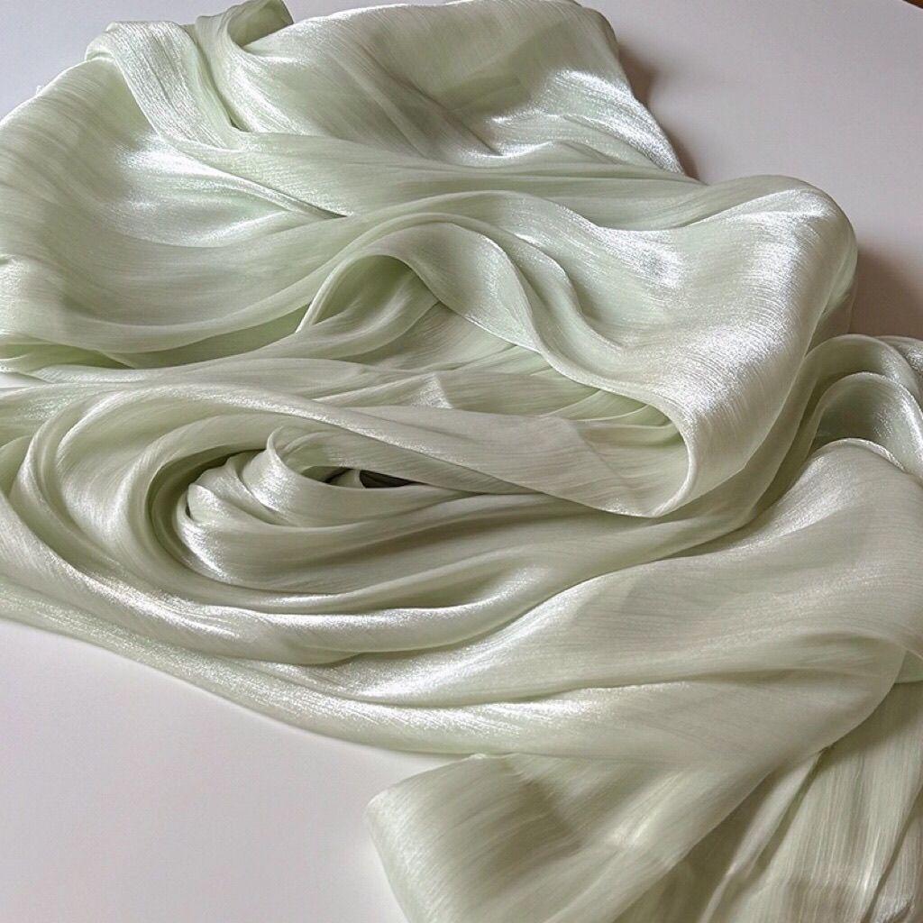 Soft shiny creased organza fabric with a smooth texture suitable for wedding dresses formal gowns and designer clothing fabrics