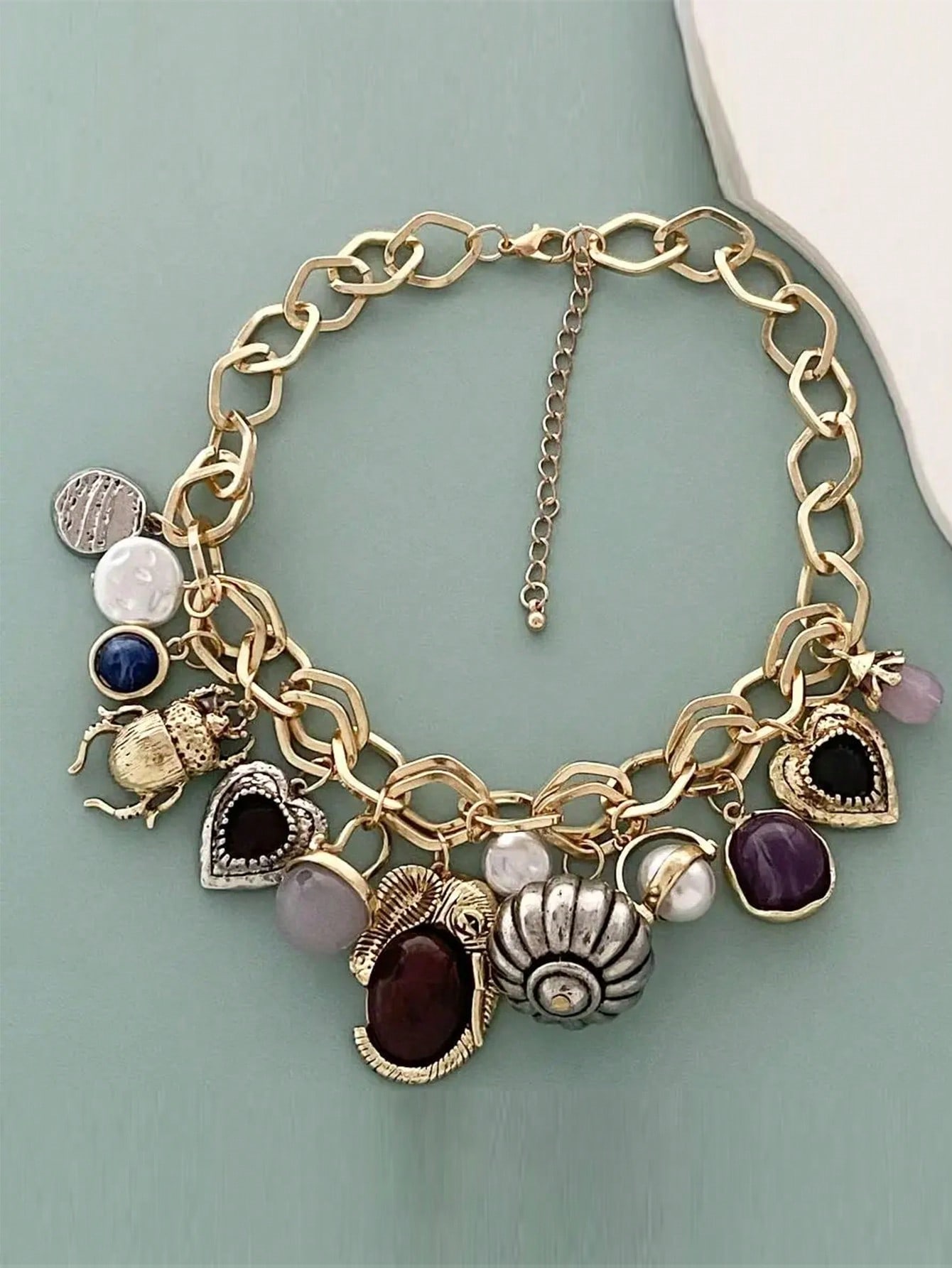 

A Chunky Chain Necklace Featuring An Engraved Heart-Shaped Pendant, Insect And Animal Motifs, And A Vintage-Style Multi-Pendant Necklace.