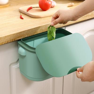 Pattumiera sospesa sulla porta dell'armadio da cucina con maniglia. Piccola pattumiera sotto il lavandino, pattumiera per rifiuti da banco montata a parete