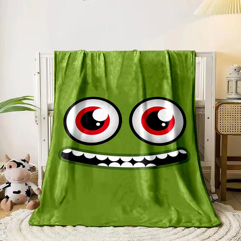 

A green face with large red eyes and a wide, toothy grin. for all seasons blanket lunch break throw gift 80cm x 120cm