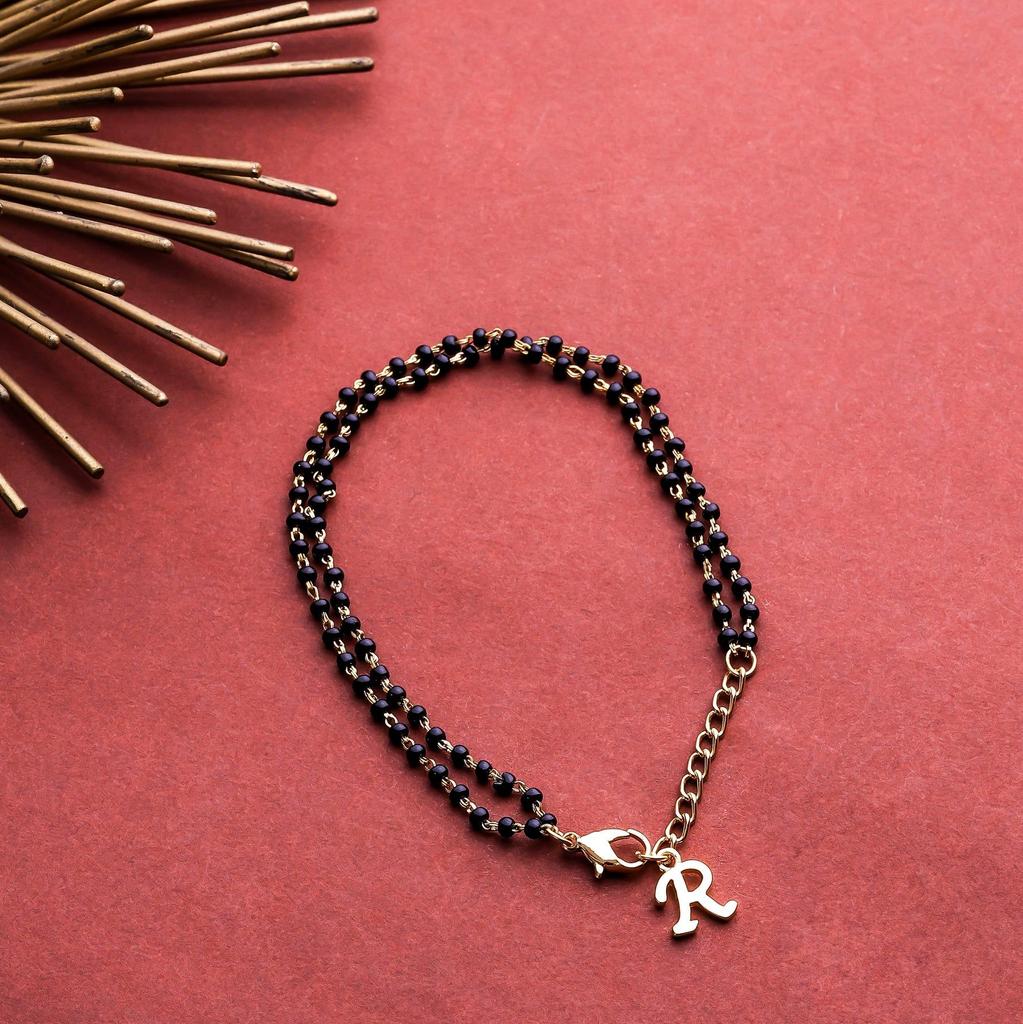 Damenarmband Estele mit einem bezaubernden vergoldeten Buchstaben „R“ und schwarzen Perlen