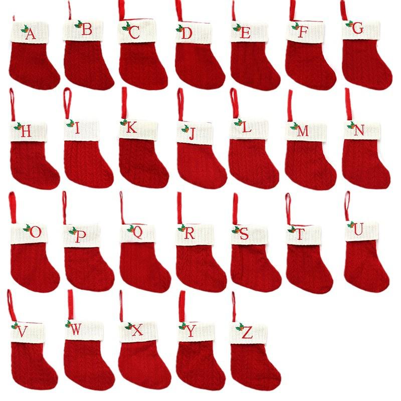 Weihnachtsdekorationen: Rote gestrickte Kinderstrümpfe mit gestickten Buchstaben