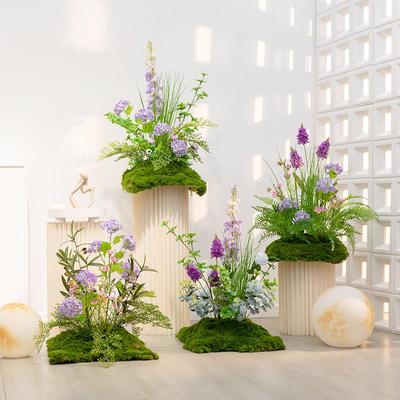 Künstliche Blumenlandschaft: Zimmerpflanzen, Grasbüschel und bionische Blumengesteckdekoration.