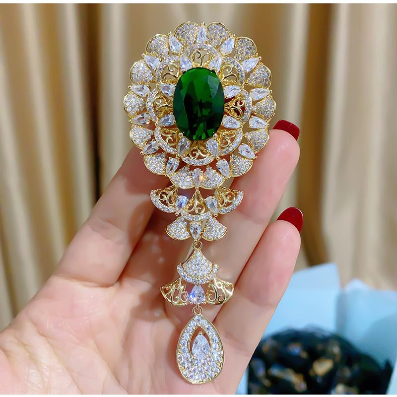 

Легкая роскошная брошь с полыми бриллиантами и элегантной пряжкой в ​​стиле ретро из зеленого и красного корунда и циркона