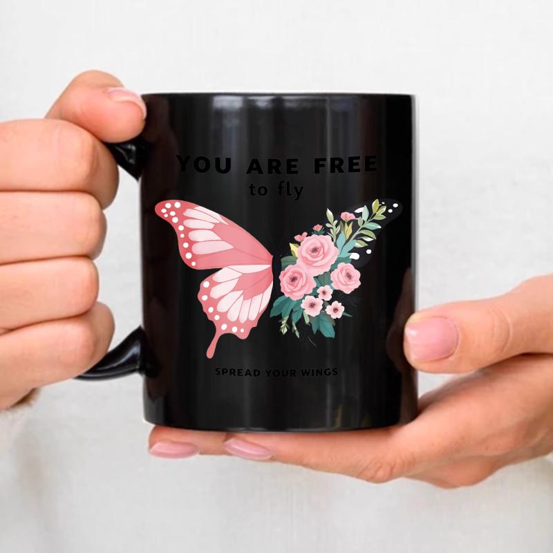 A black ceramic mug with a pink butterfly and floral design and an inspirational quote to You fly free, spread your wings is p чёрный