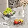 Transparente Obst- und Snack-Präsentationsplatte mit hohem Fuß: Modernes Licht-Luxus-Design für Wohnzimmer-Couchtische.