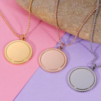 Collana in acciaio inossidabile con ciondolo rotondo e logo inciso al laser con motivo geometrico a pizzo.