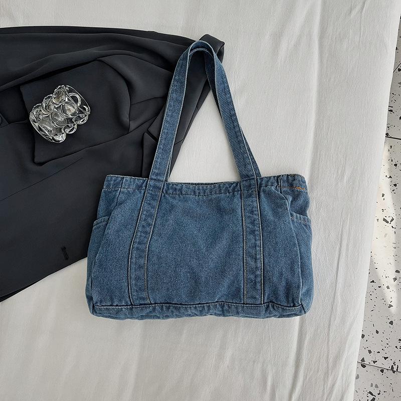 En denimväska med stor kapacitet En avslappnad och mångsidig toteväska för skola, pendling och en axelväska