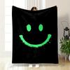 Uma carinha sorridente verde brilhante com respingos de tinta sobre um fundo preto. cobertor para todas as estações manta para pausa para almoço presente