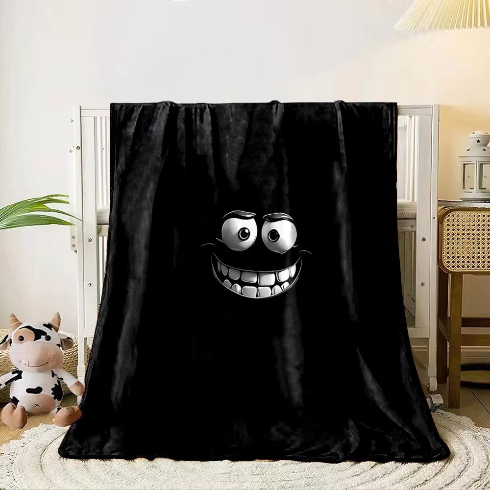 A glowing, cartoonish face with wide eyes and a big toothy grin on black. for all seasons blanket lunch break throw gift